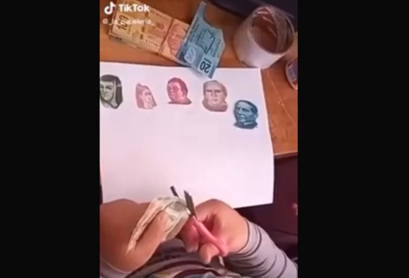 Niña recorta billetes para ilustrar su tarea