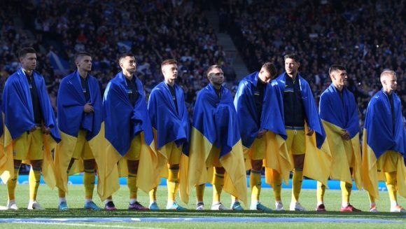 Selección ucraniana de futbol  se envuelven en su bandera durante el himno y piden alto a la guerra