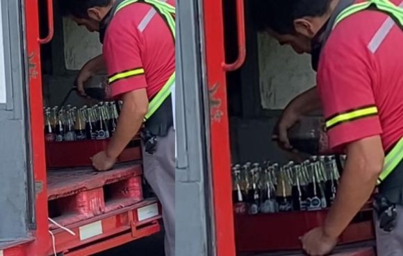 Trabajador de Coca-Cola rellena botellas sucias de refresco